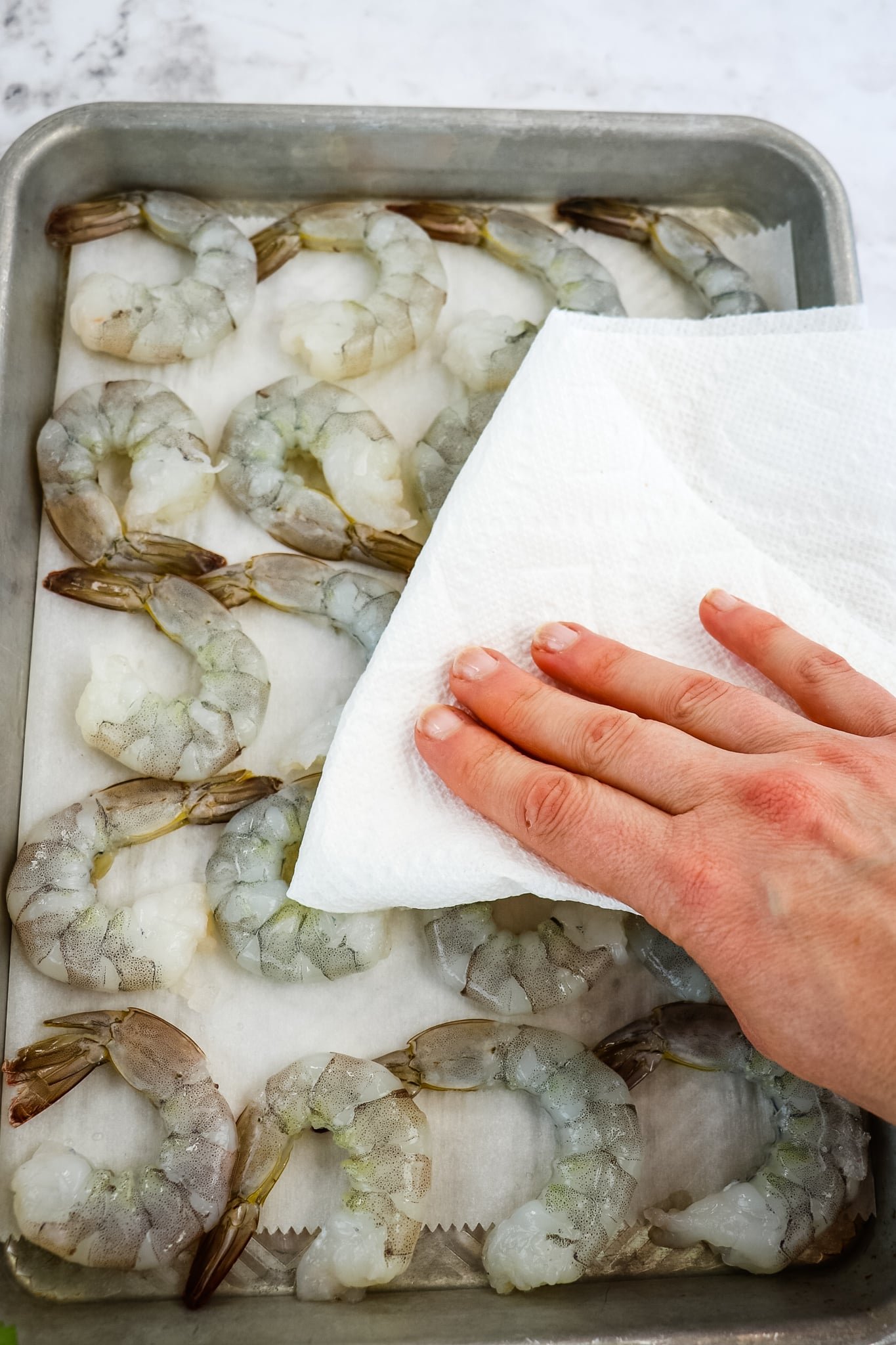 Raw shrimp being dried with a paper towel.