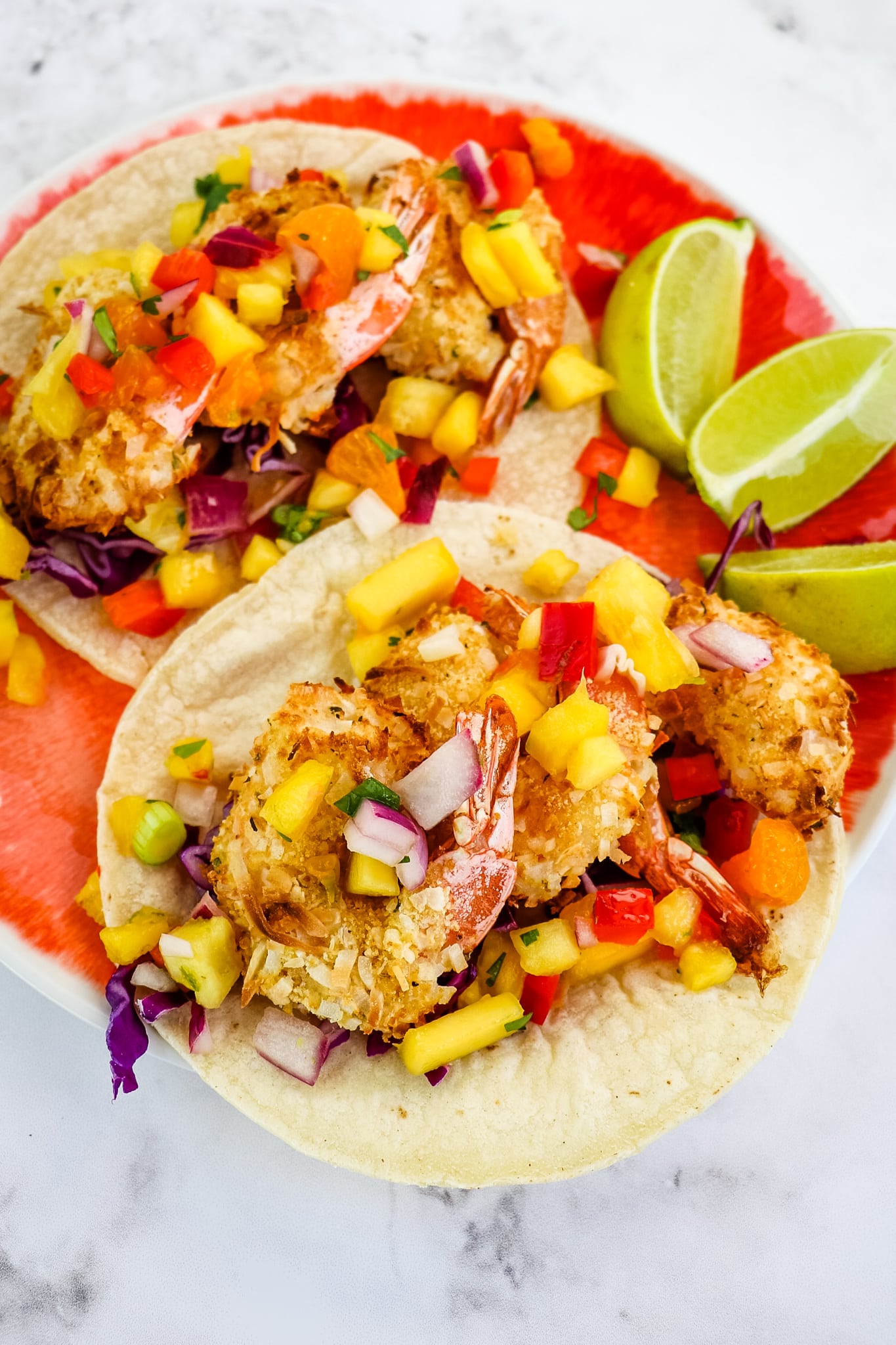 Coconut shrimp served as tacos with pineapple mango salsa and lime wedges.