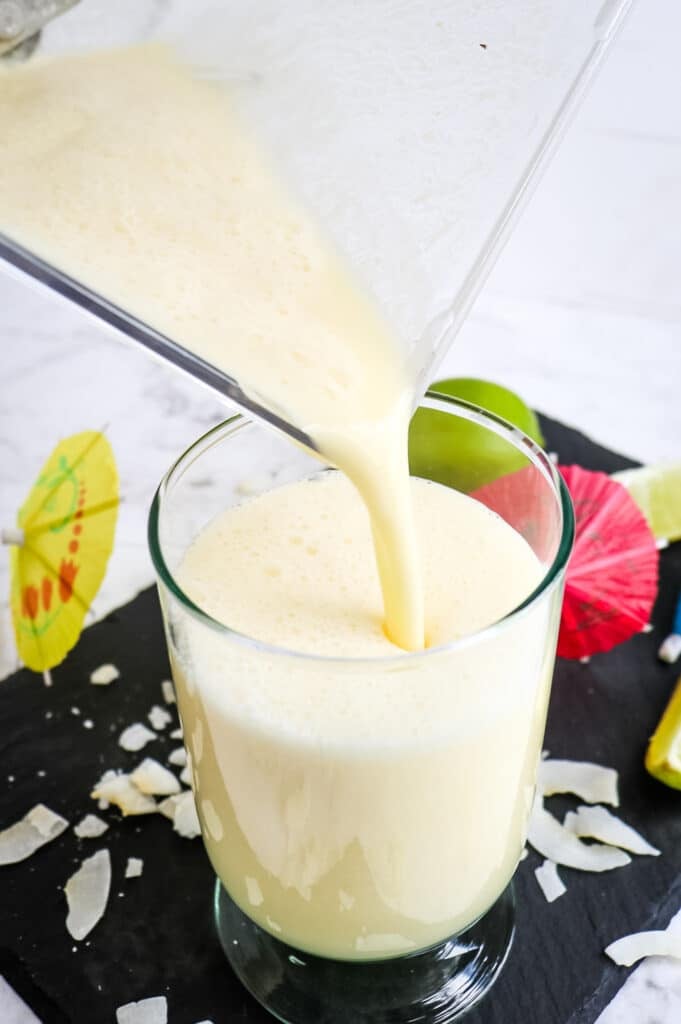 Frozen pineapple daiquiri being poured into a glass.