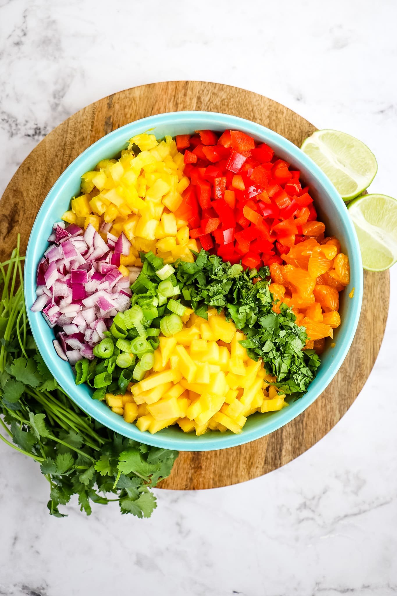 Chopped ingredients for pineapple mango salsa in blue bowl.