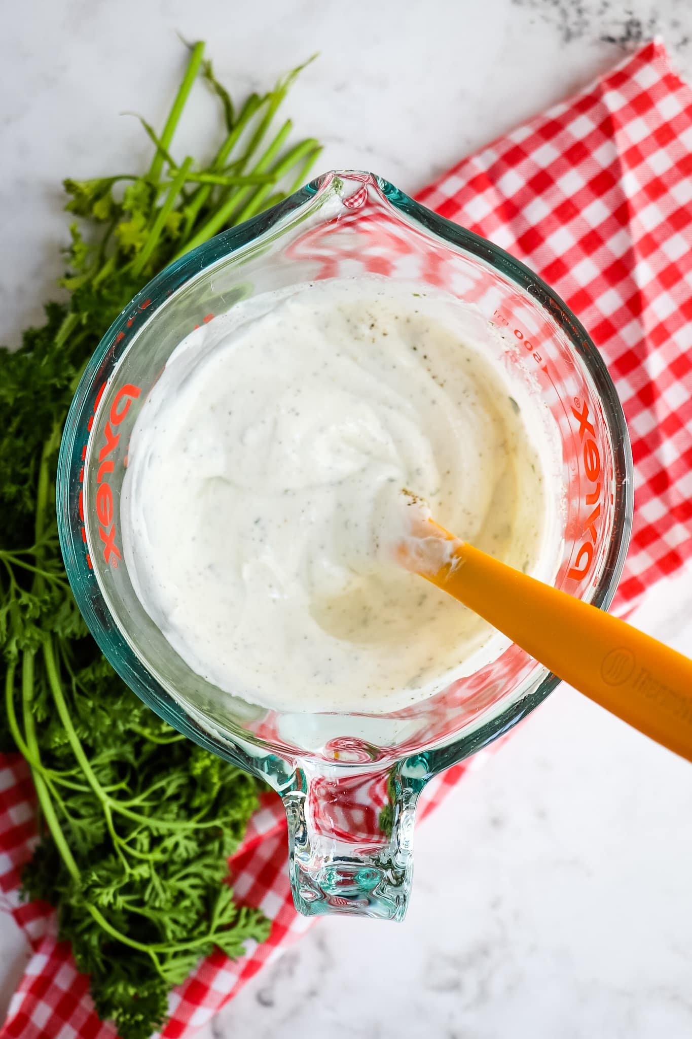 Ranch dressing mixed together with a spatula, parsley on the side.