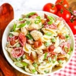 Bacon ranch pasta salad in white bowl, with tomatoes on the side.