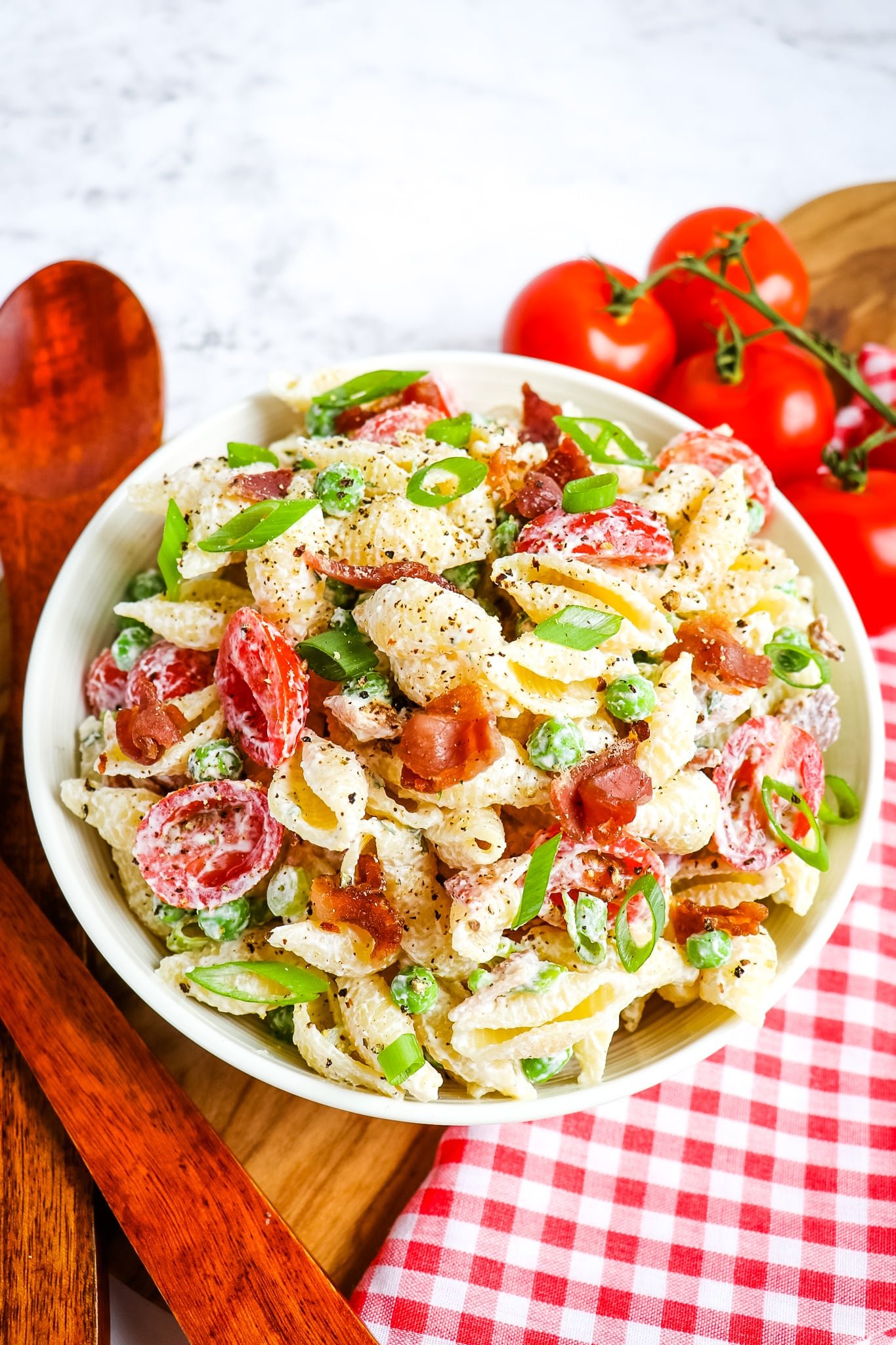 Bacon ranch pasta salad in white bowl, with tomatoes on the side.