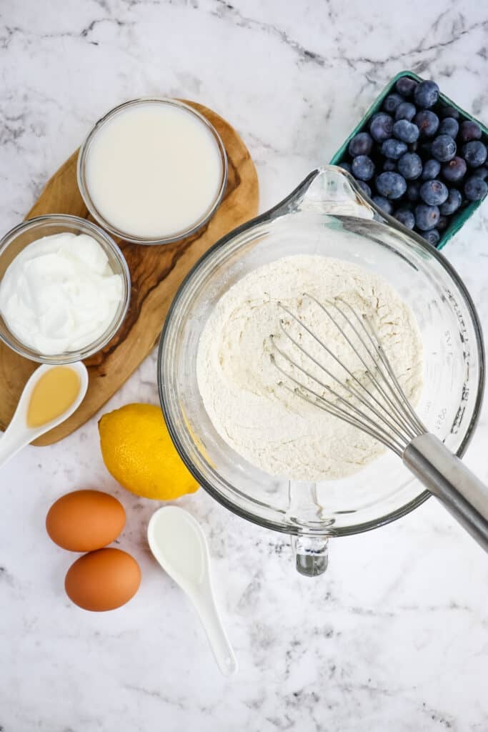 Ingredients needed to make lemon blueberry loaf, with dry ingredients in mixing bowl.