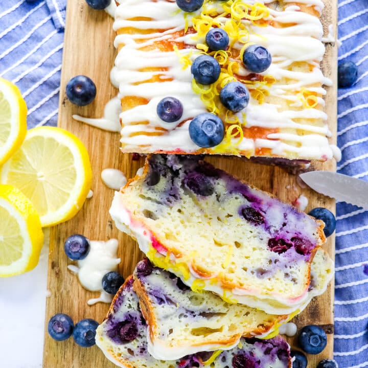 Lemon blueberry loaf, with three slices, garnished with lemon slices and fresh blueberries.