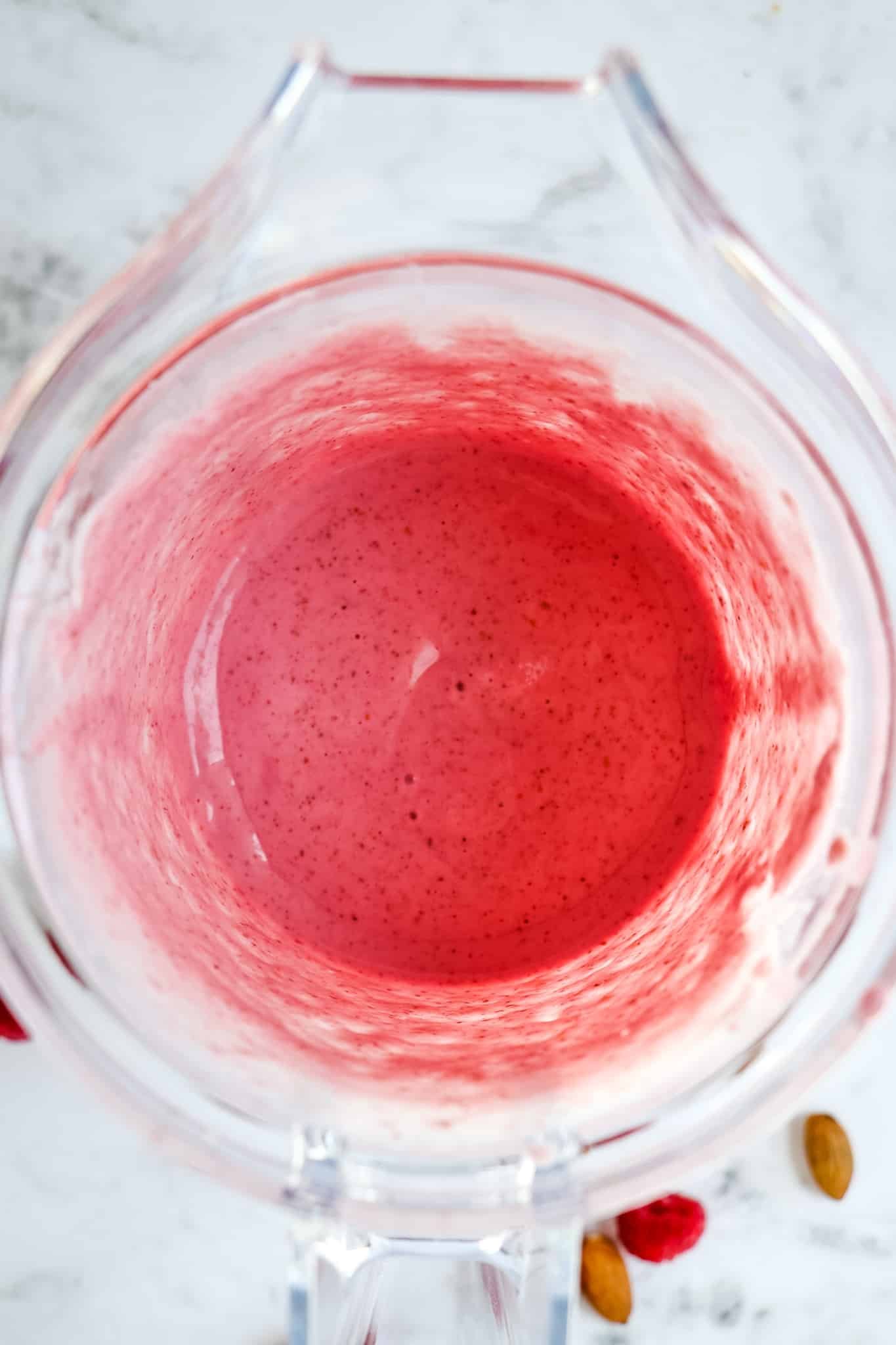 Raspberry smoothie recipe blended in a blender jar.