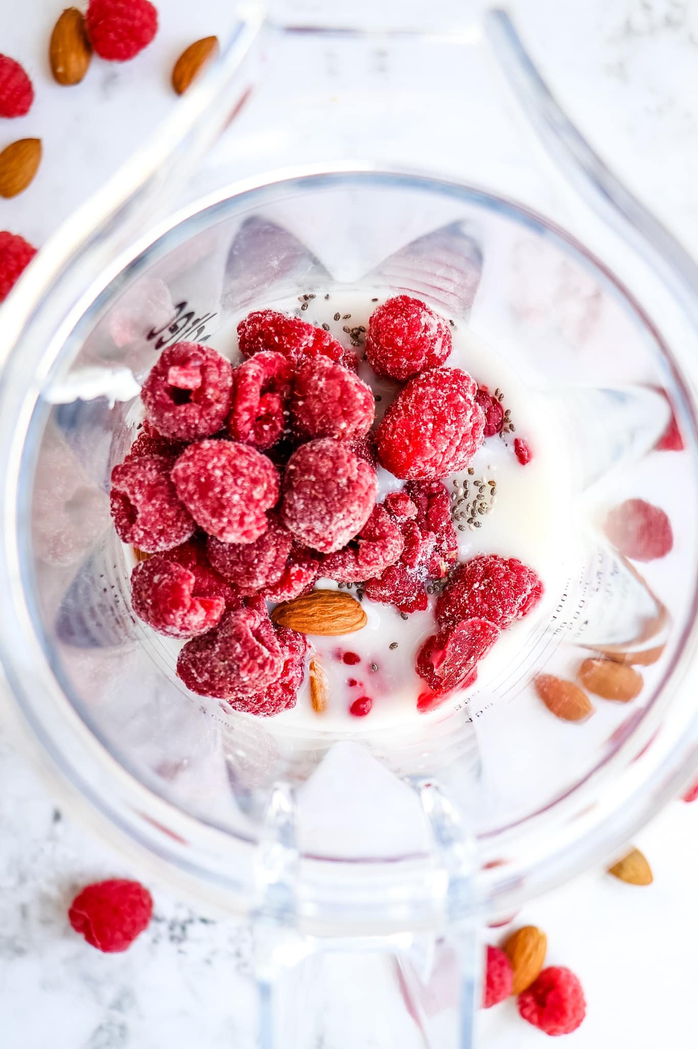 Frozen raspberries, almonds and greek yogurt in blender jar.