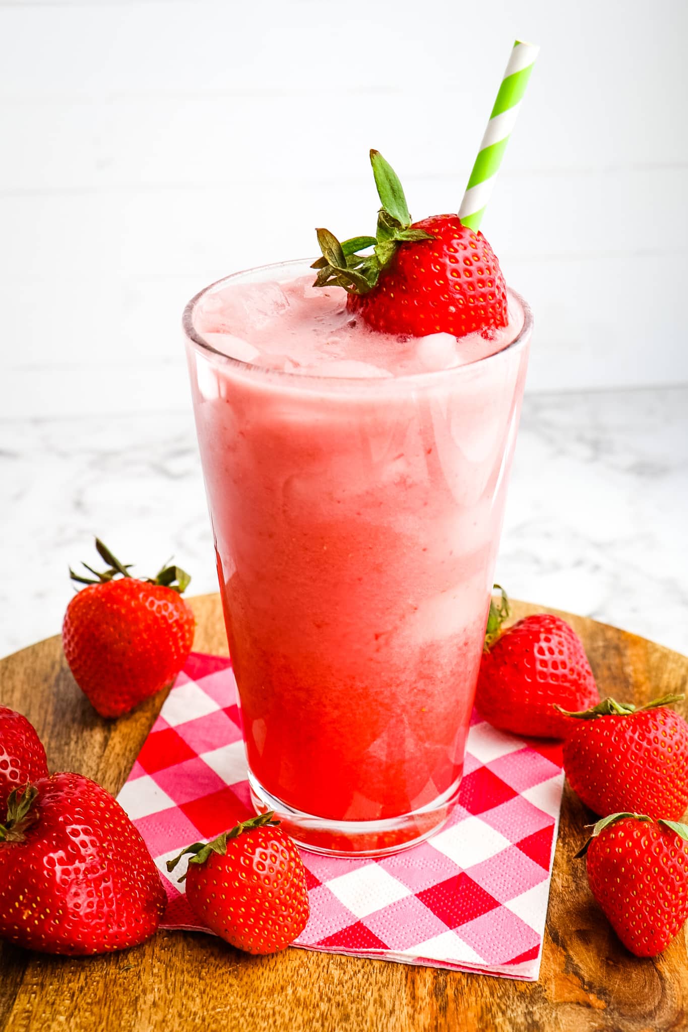 Starbucks pink drink recipe garnished with strawberries and topped with strawberry and straw.