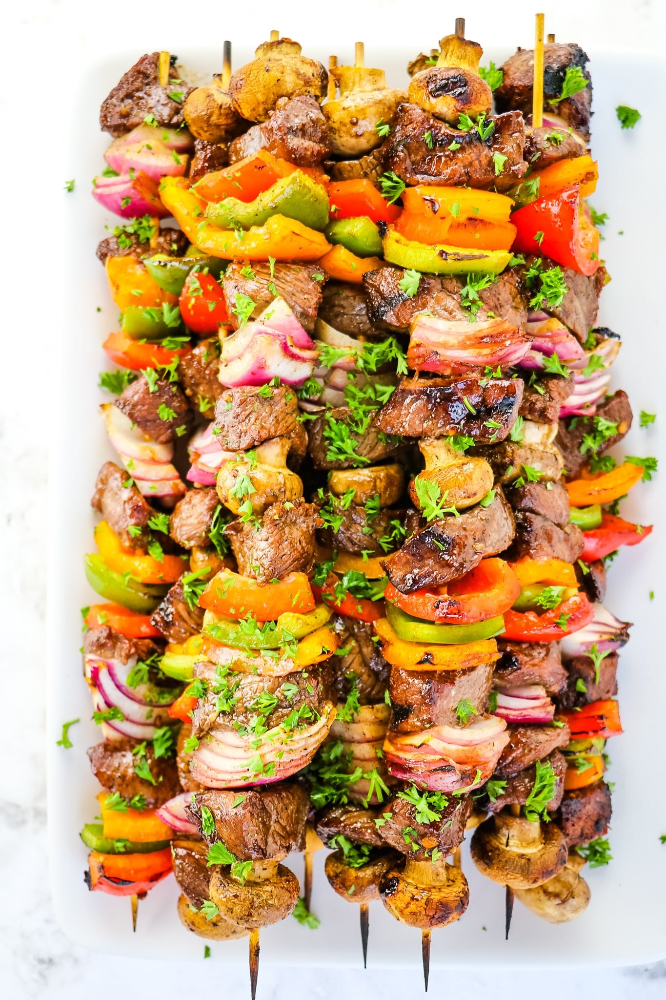 Grilled steak kabobs, topped with chopped parsley.