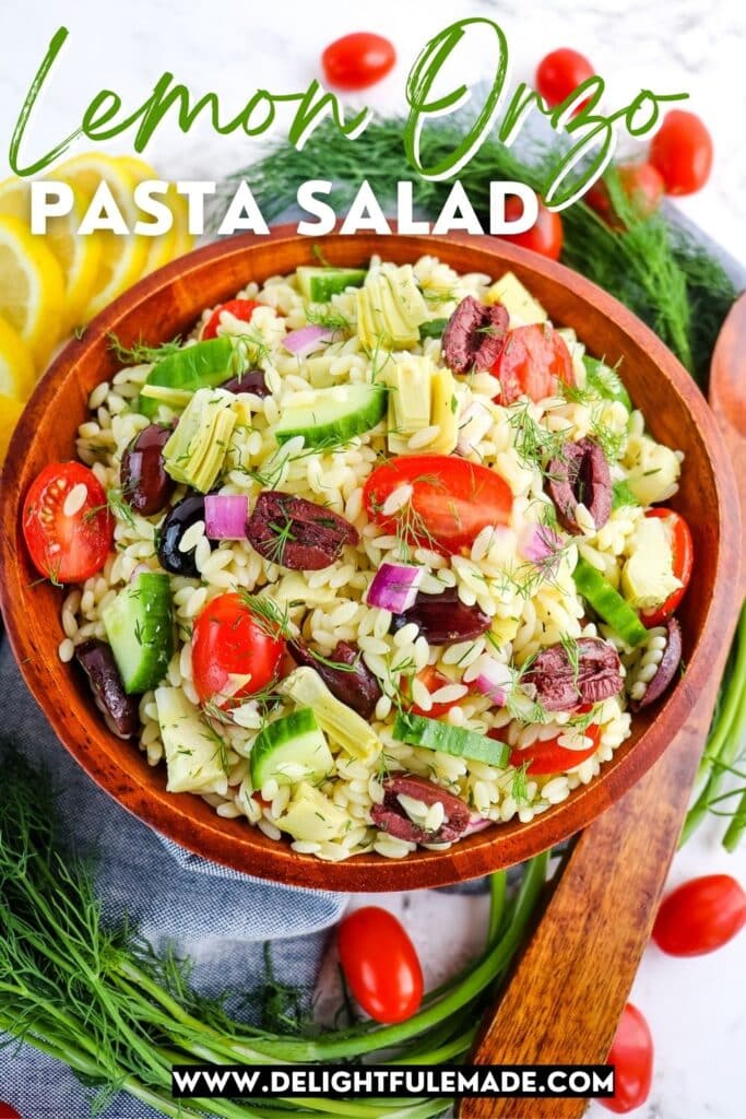 Bowl of lemon orzo pasta salad, with tomatoes, olives, cucumbers and dill.