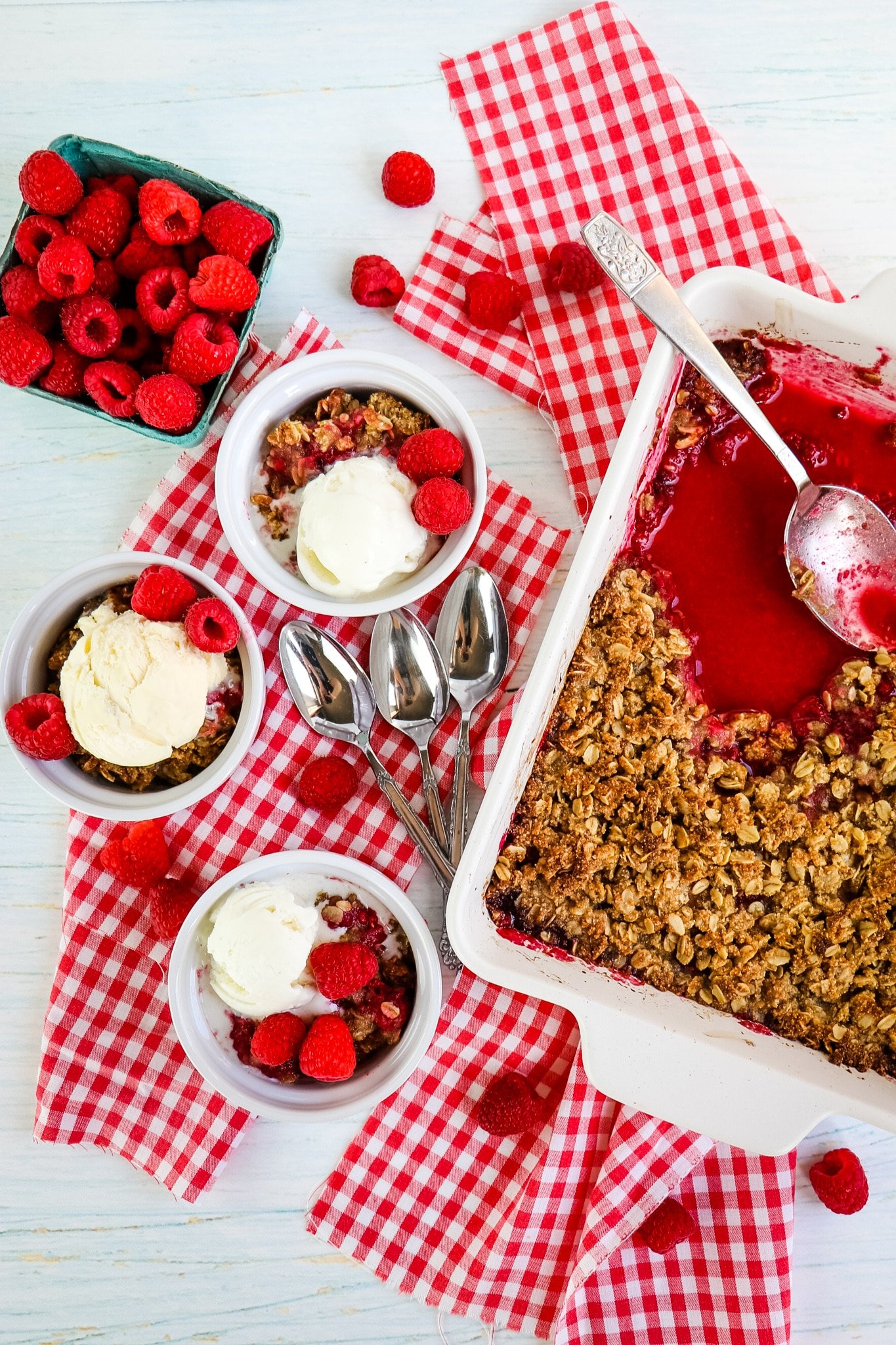 Raspberry crumble in baking dish and spooned into three bowls with ice cream.