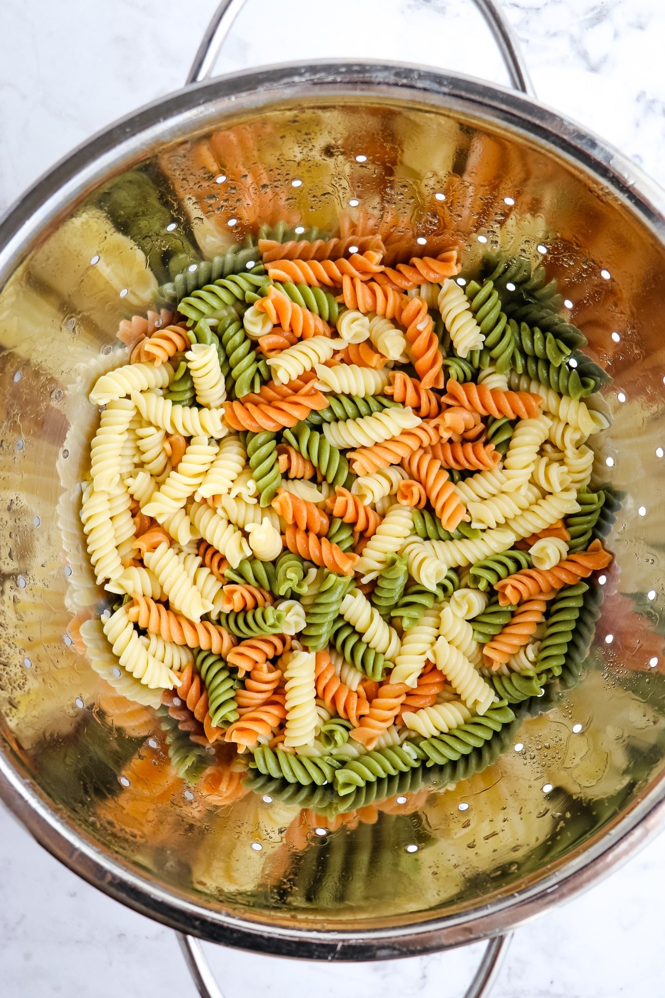 Tri-color rotini pasta drained in collander.