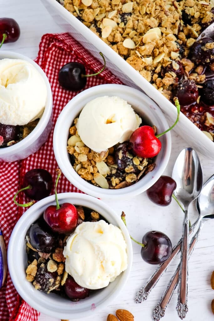 Small dishes of cherry crisp, topped with scoops of vanilla ice cream.