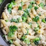 Chicken and broccoli alfredo in a skillet, topped with Parmesan cheese.