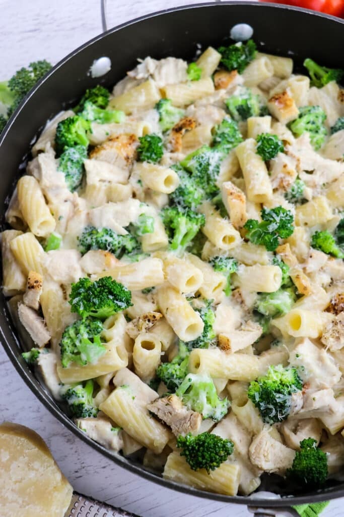 Chicken and broccoli alfredo in a skillet, topped with Parmesan cheese.