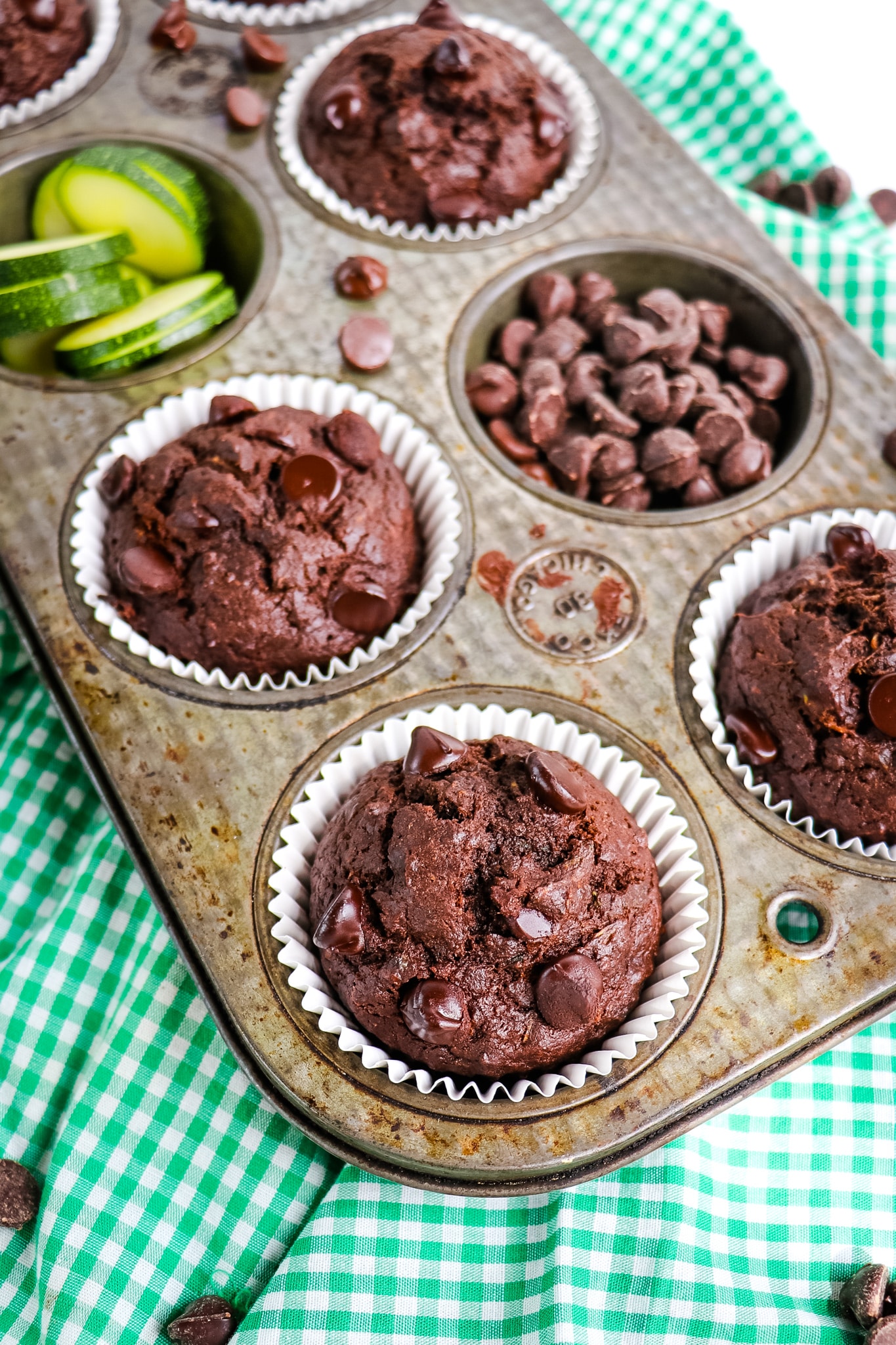 Chocolate zucchini muffins in muffin tin, with white liners.