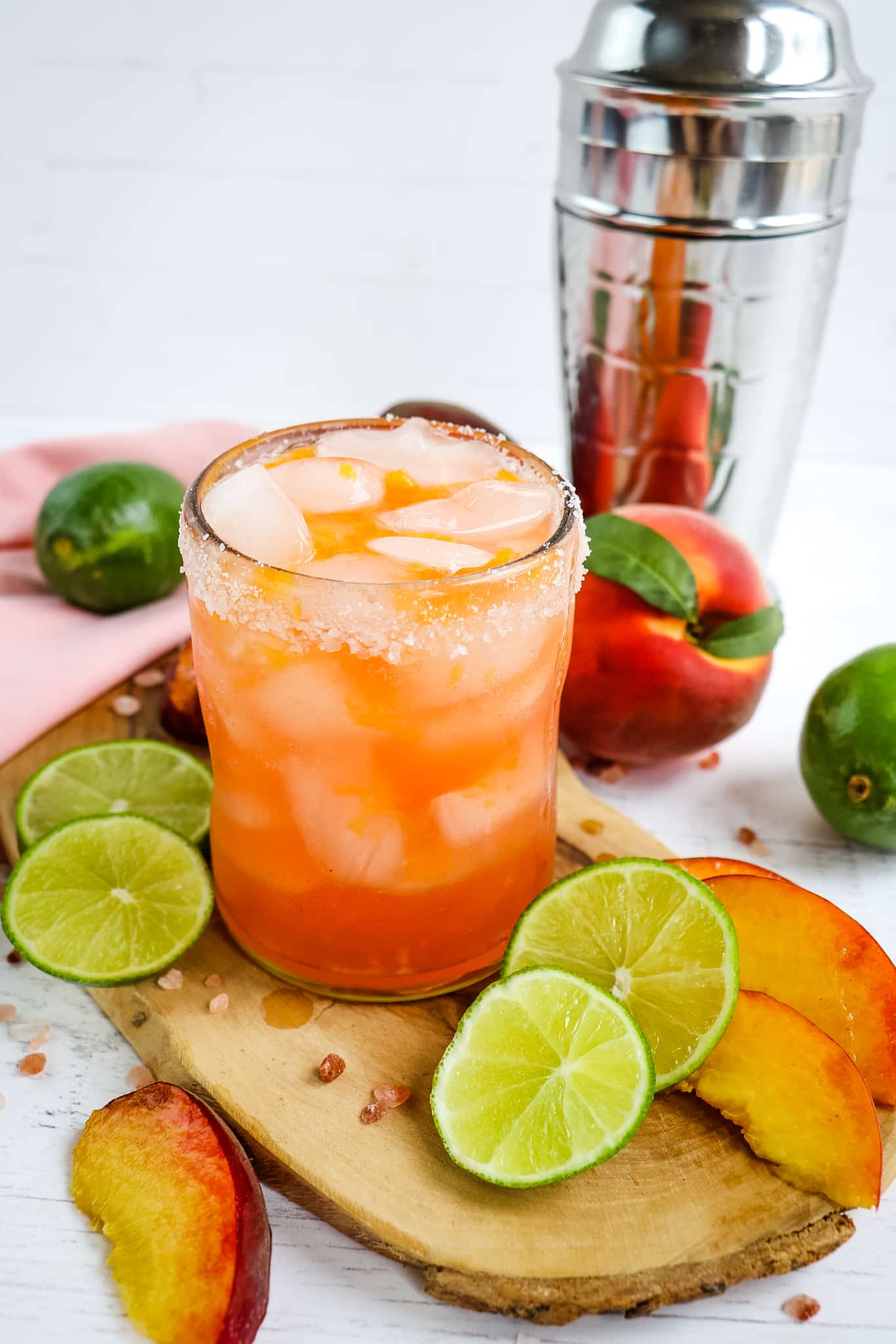 Peach margarita in a salted glass with lime and peach slices.