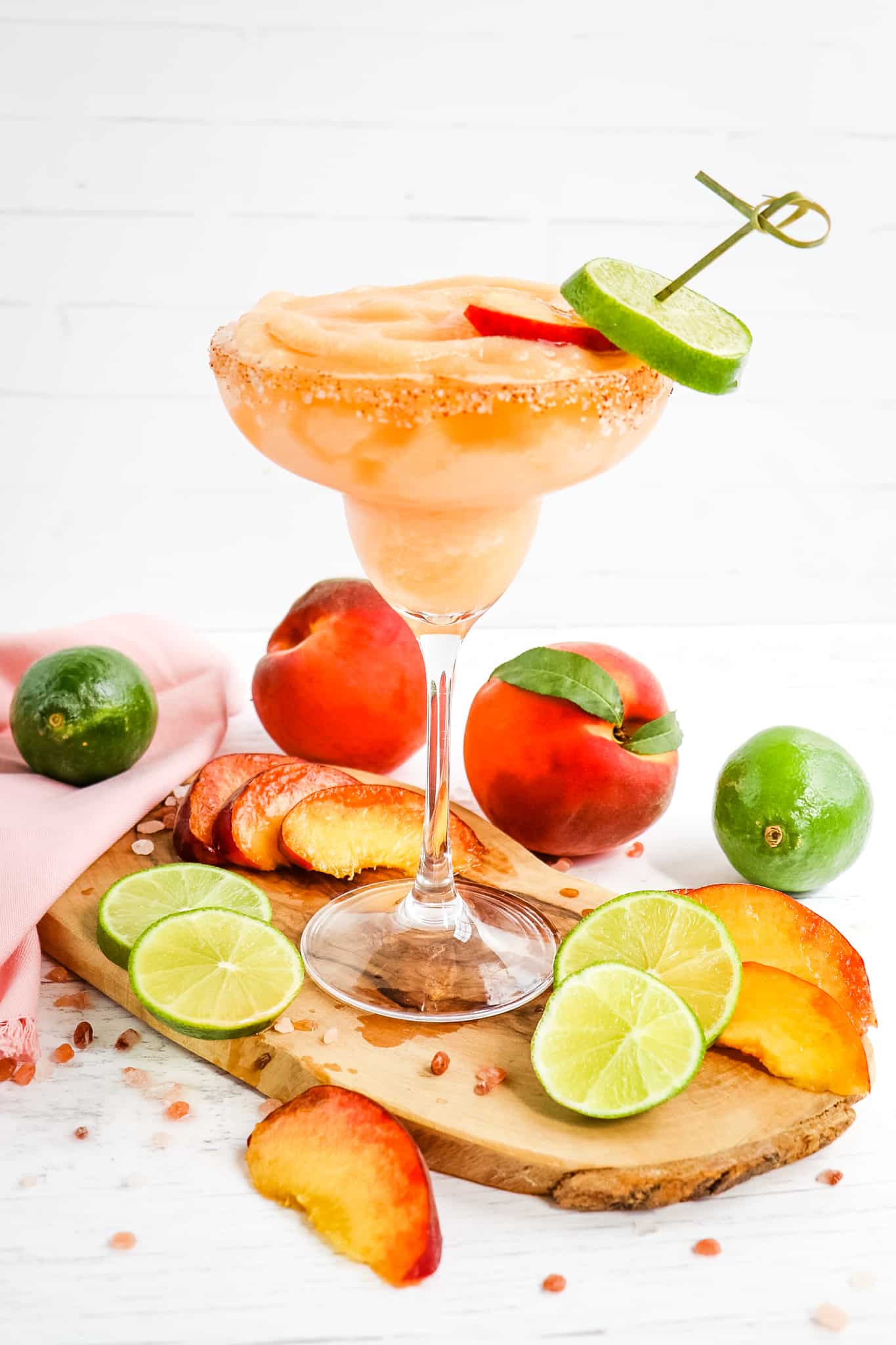 Frozen peach margarita, garnished with peach and lime slices.