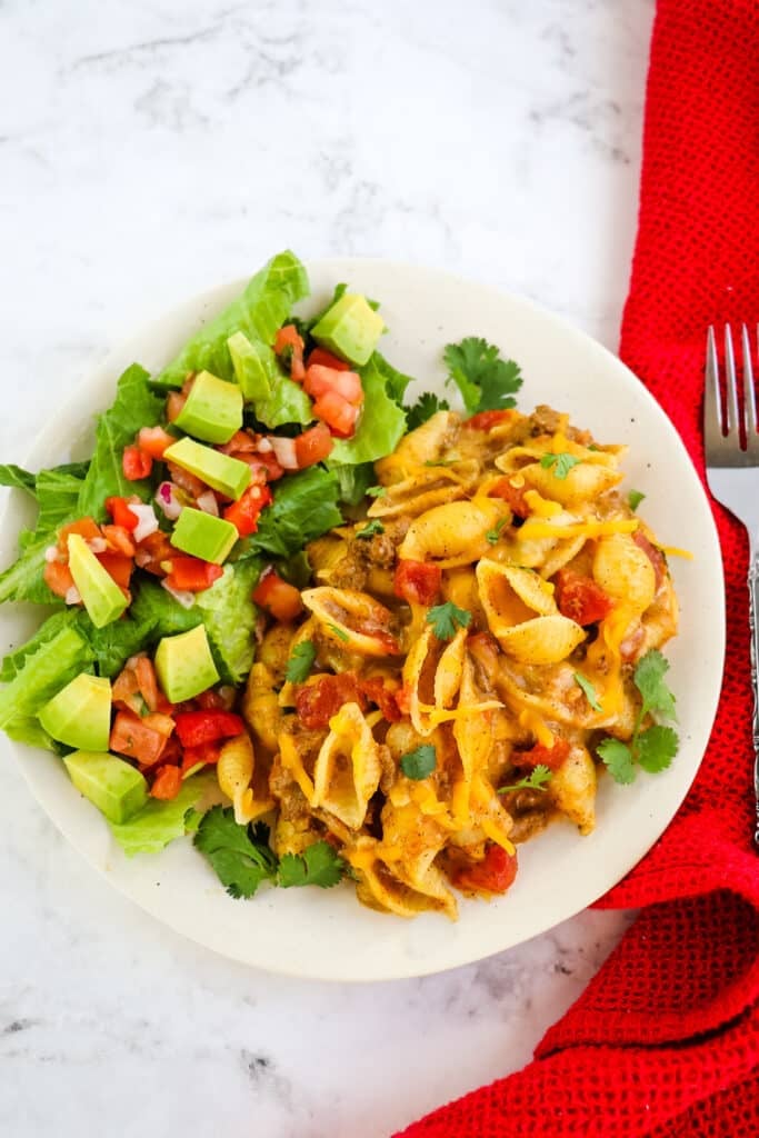 Taco mac and cheese on plate with side salad.