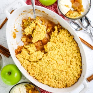 Apple cobbler with cake mix in baking dish and two bowls on the side with ice cream.