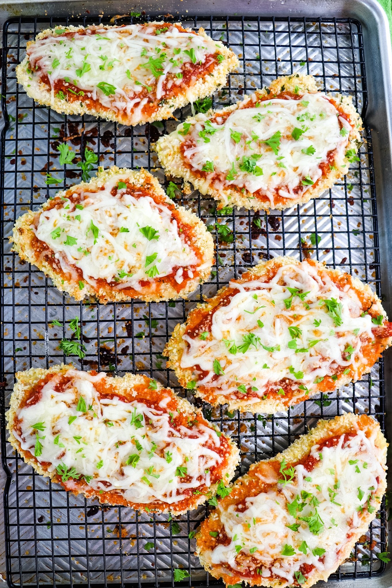 Parmesan crusted chicken topped with cheese and chopped parsley.