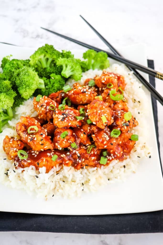 Honey sesame chicken on rice, served with broccoli.