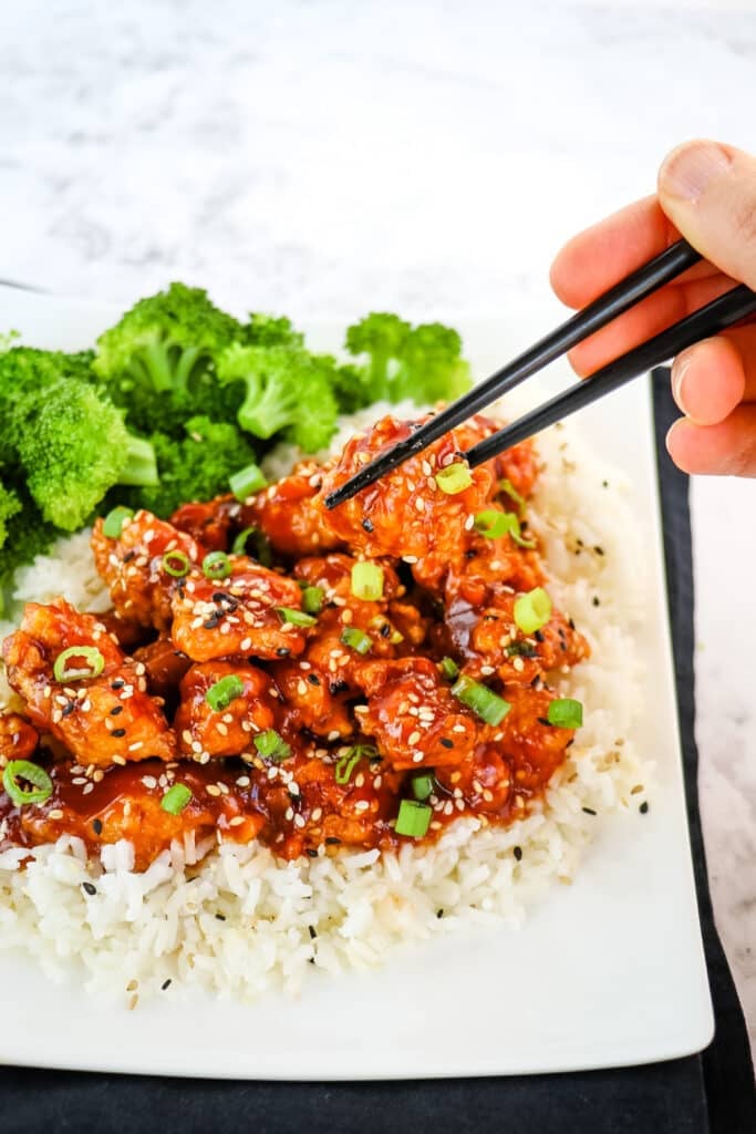 Honey sesame chicken on plate, with chopsticks.