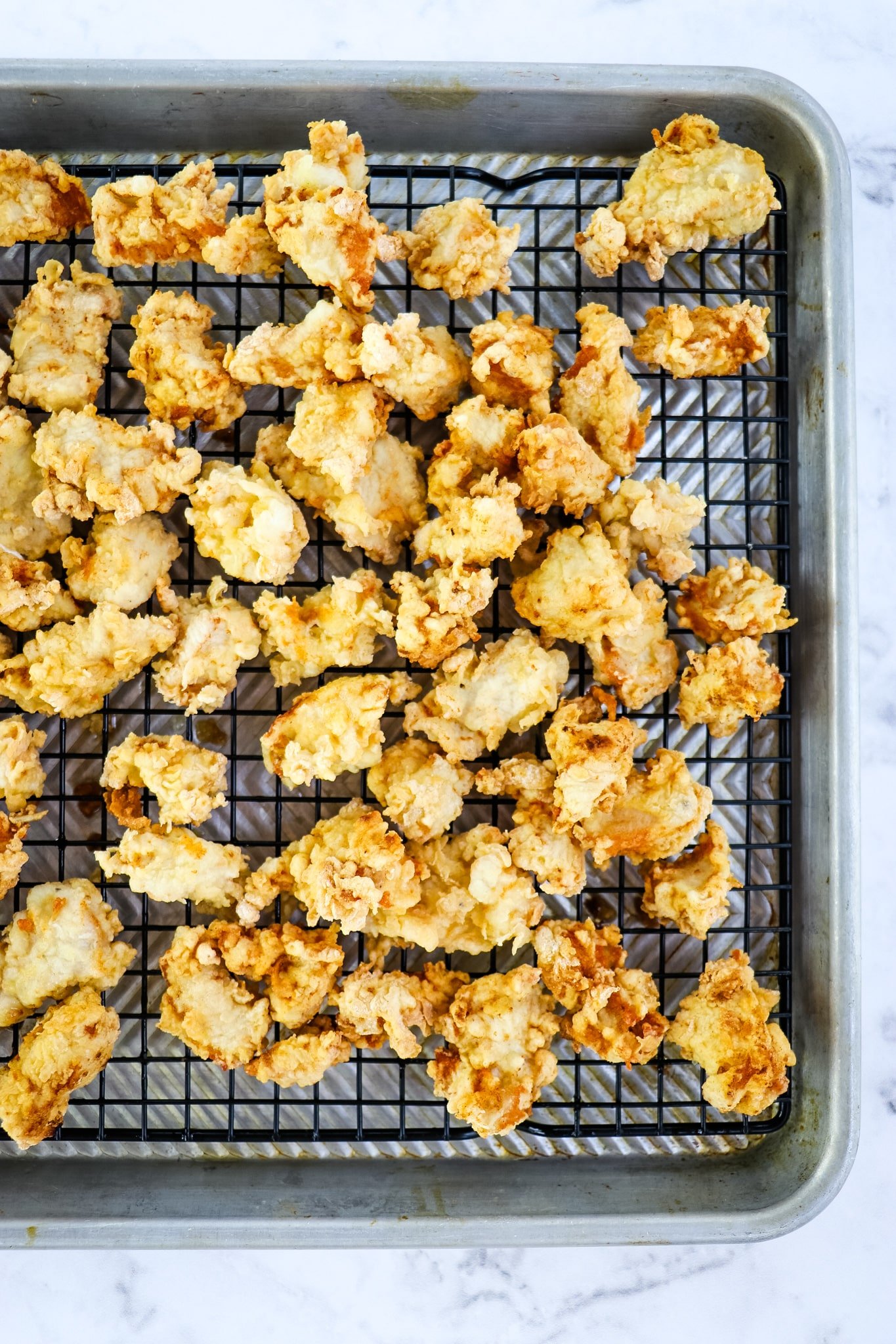 Chunks of fried chicken on rack to drain grease.