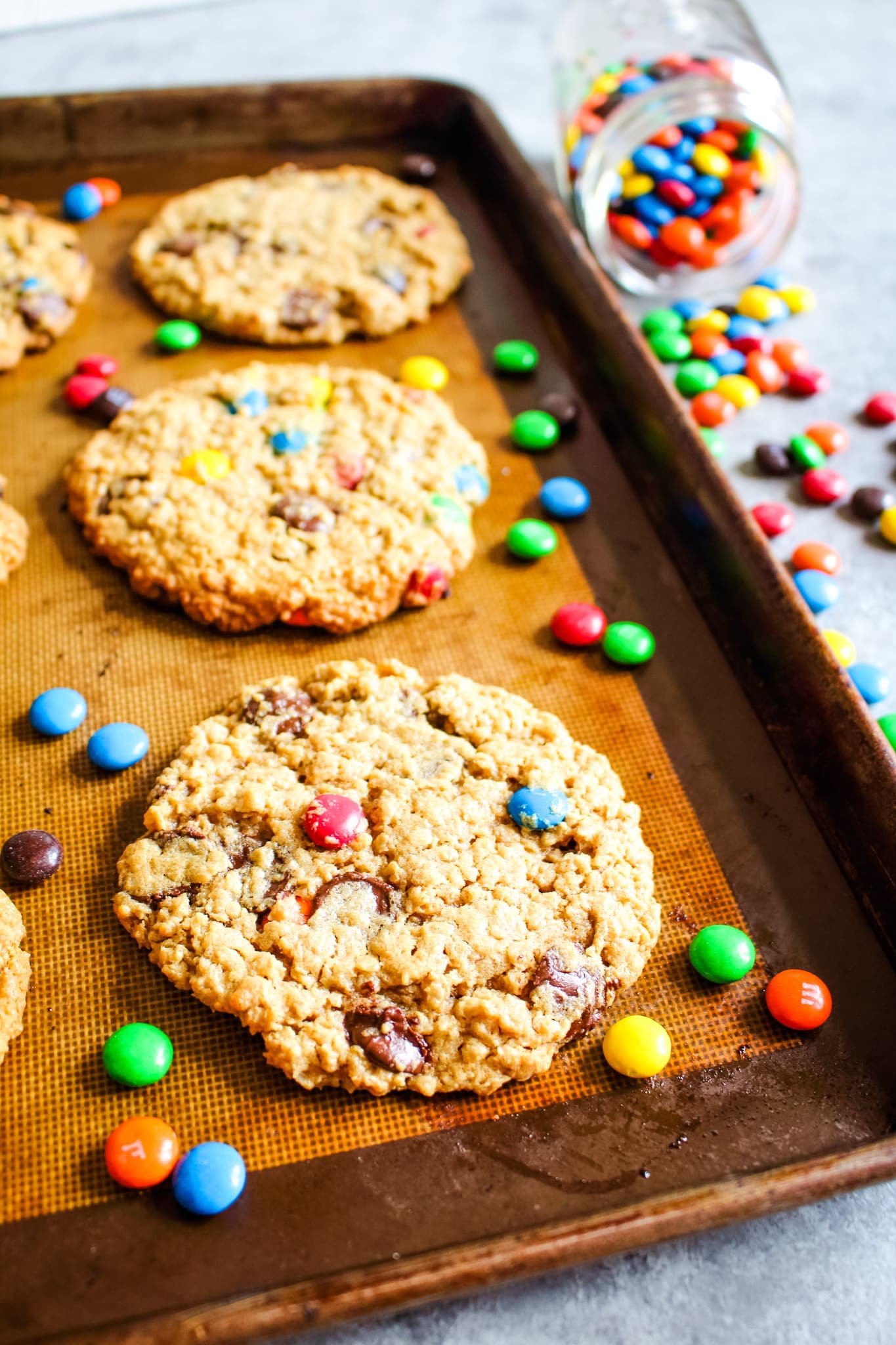 Monster cookies on baking sheet with M&M's on the side.