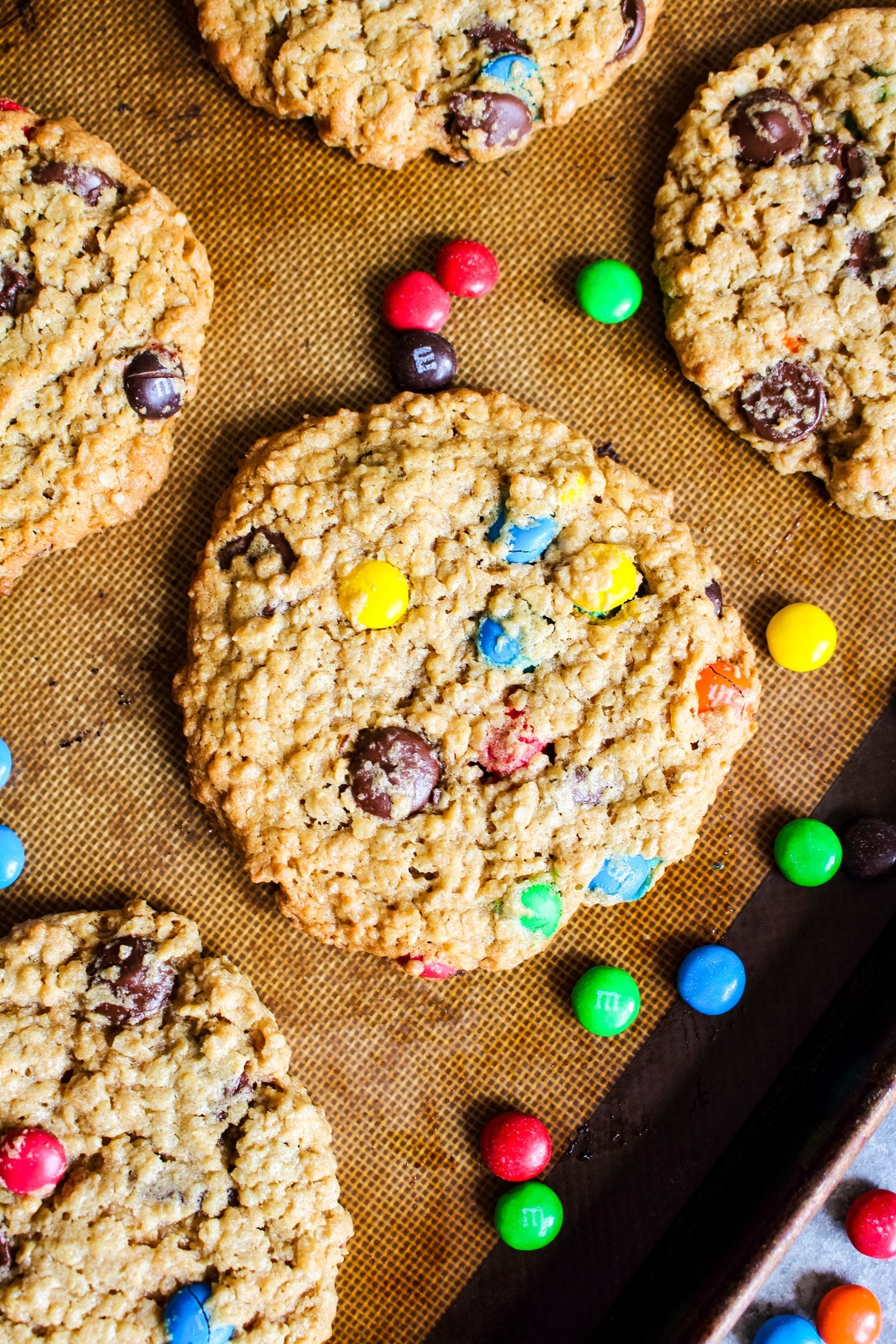 Monster cookies on baking sheet with M&M candies as a garnish.