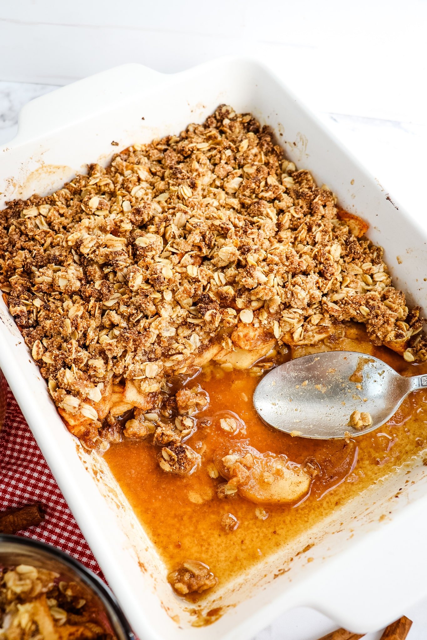 Healthy apple crumble with half removed, spoon in the center of dish.