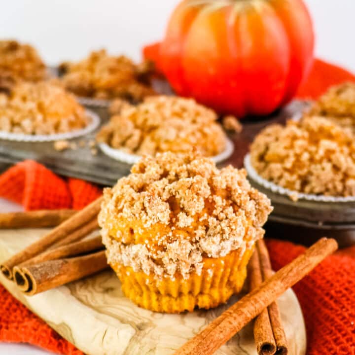 Healthy pumpkin muffins topped with cinnamon streusel topping, cinnamon sticks on the side.
