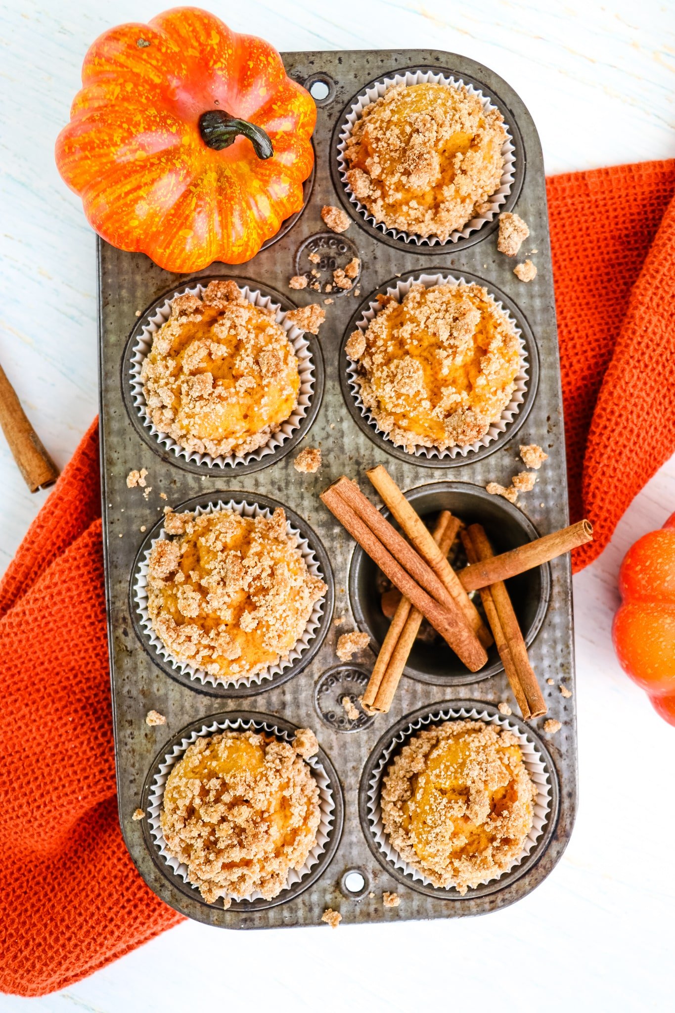 Healthy pumpkin muffins in muffin tin, with pumpkin and cinnamon stick garnish.