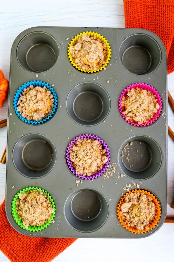 Muffin batter in muffin tin topped with cinnamon struesel.