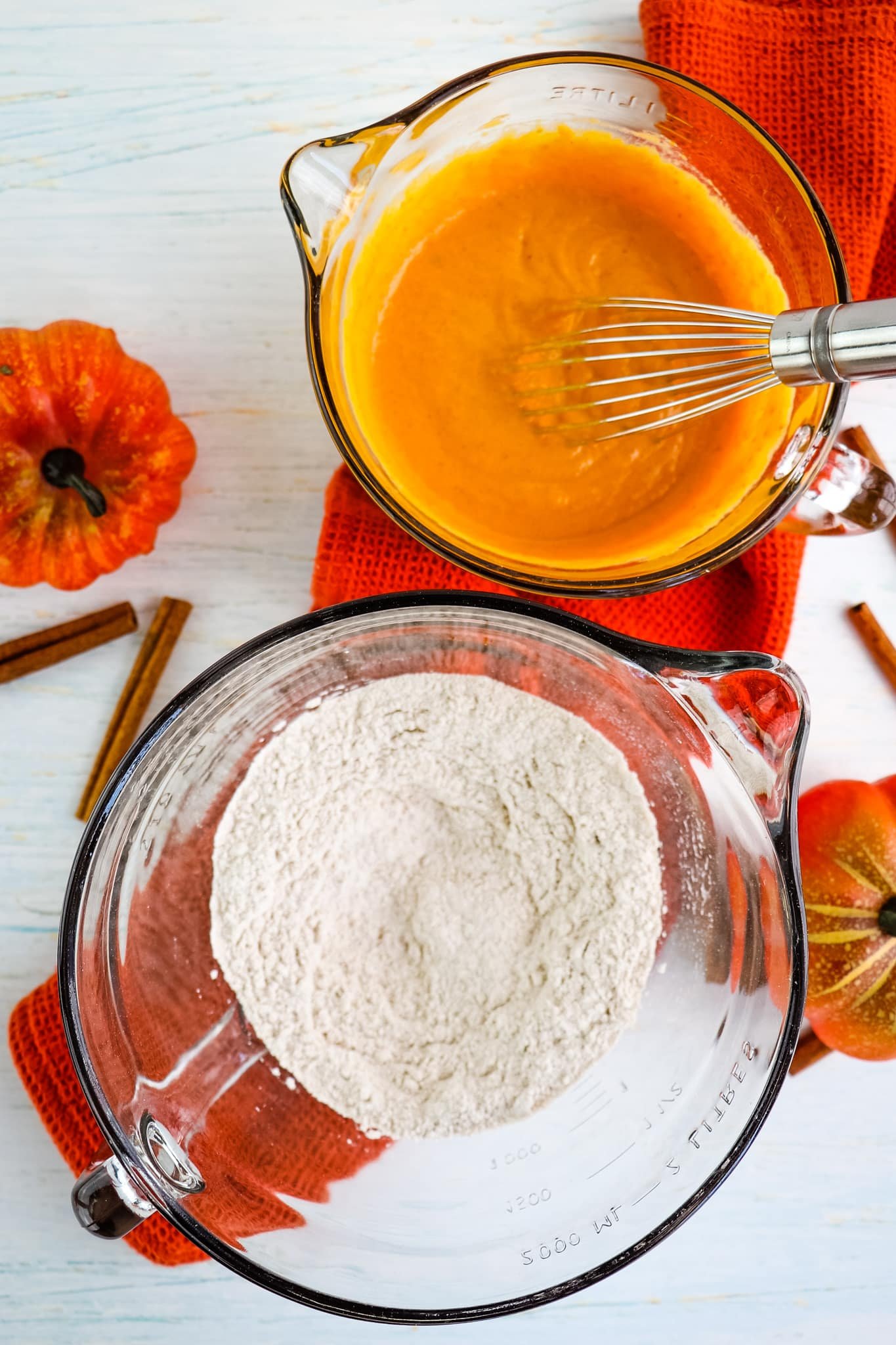 Wet and dry ingredients in two bowls to make healthy pumpkin muffins.