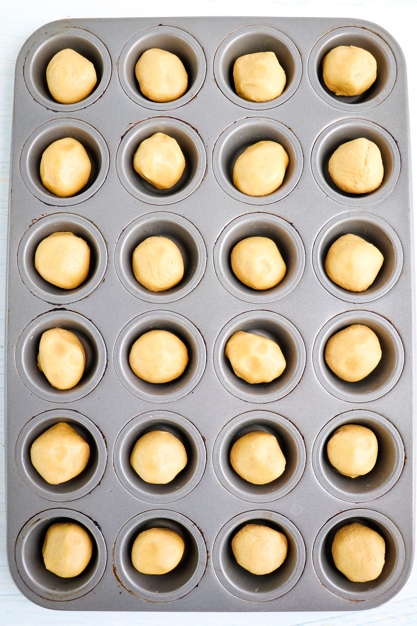 Peanut butter cookie dough rolled into balls and in a mini muffin tin.