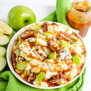 Snickers apple salad topped with a drizzle of caramel ice cream topping.