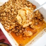 Healthy apple crumble in baking dish with spoon serving the apple crumble.