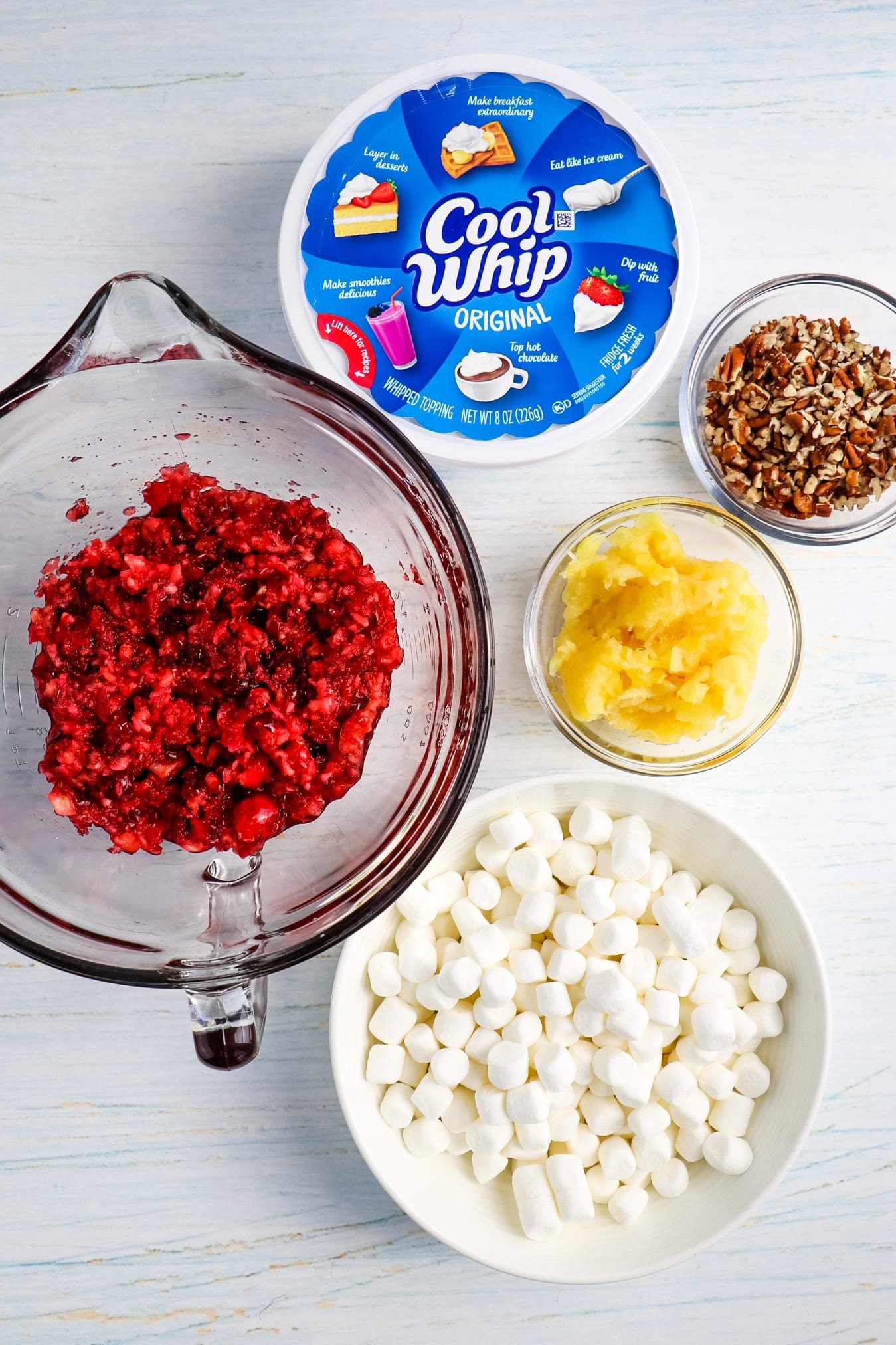 Chopped cranberries in bowl with other ingredients for cranberry fluff on the side.