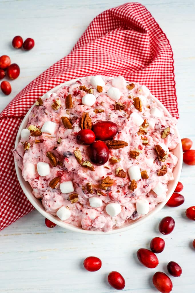 Bowl of cranberry fluff topped with fresh cranberries, pecans and marshmallows.