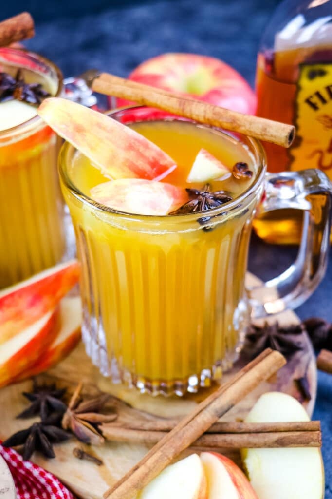 Fireball apple cider hot toddy in mug with apple slices and cinnamon sticks.