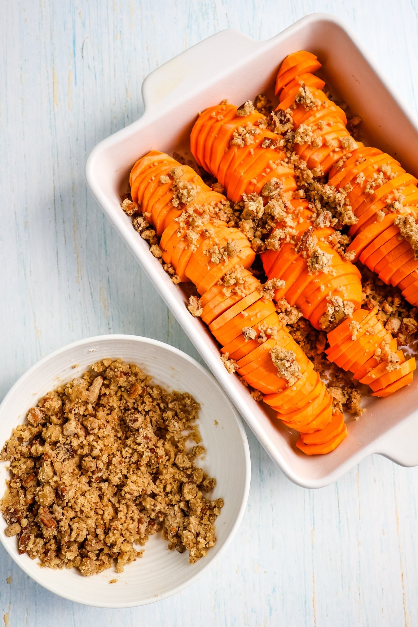 Brown sugar pecan crumble topping in bowl and on top of sliced sweet potatoes.