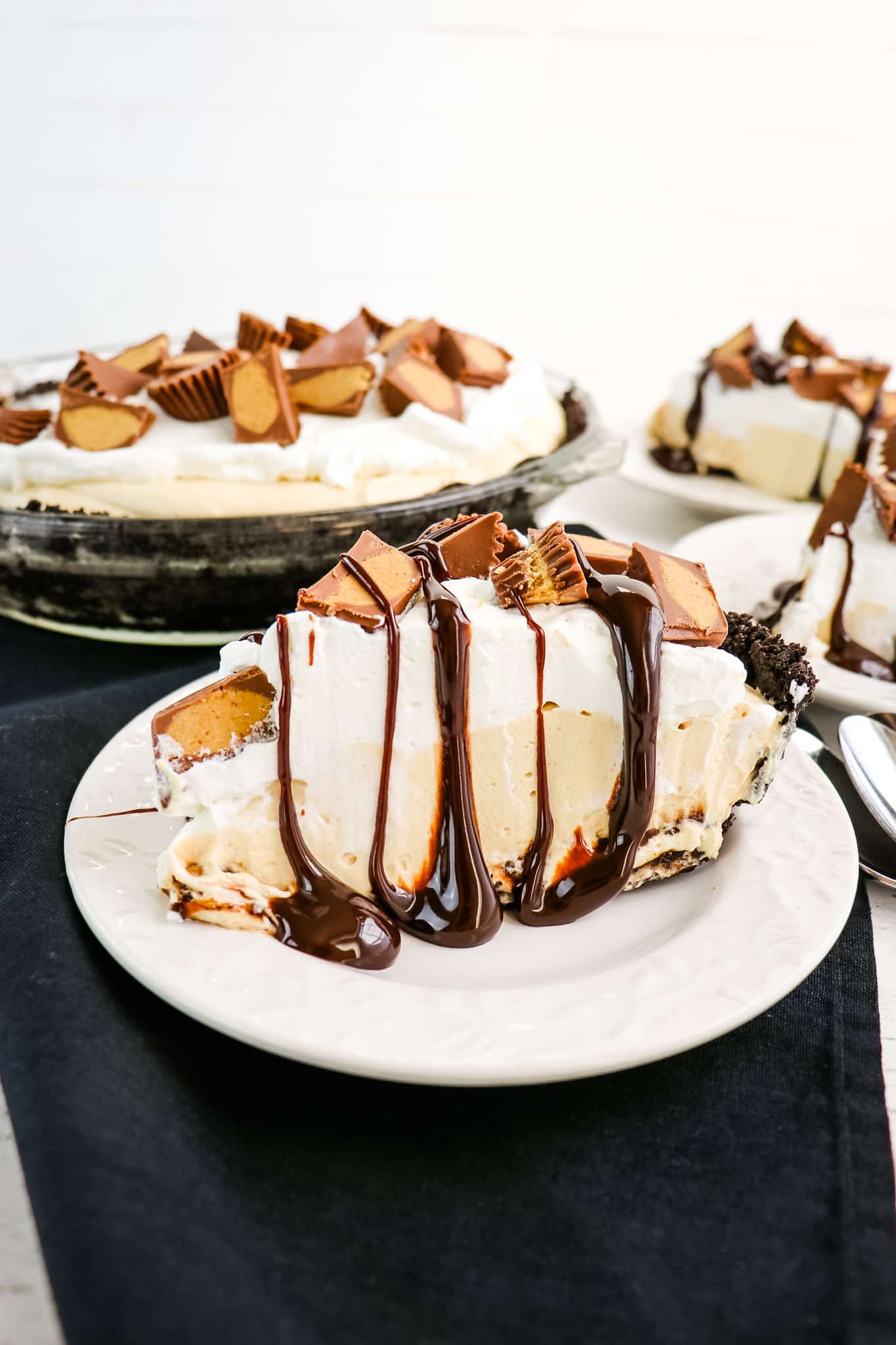 Slice of Reese's pie topped with peanut butter cups and hot fudge.