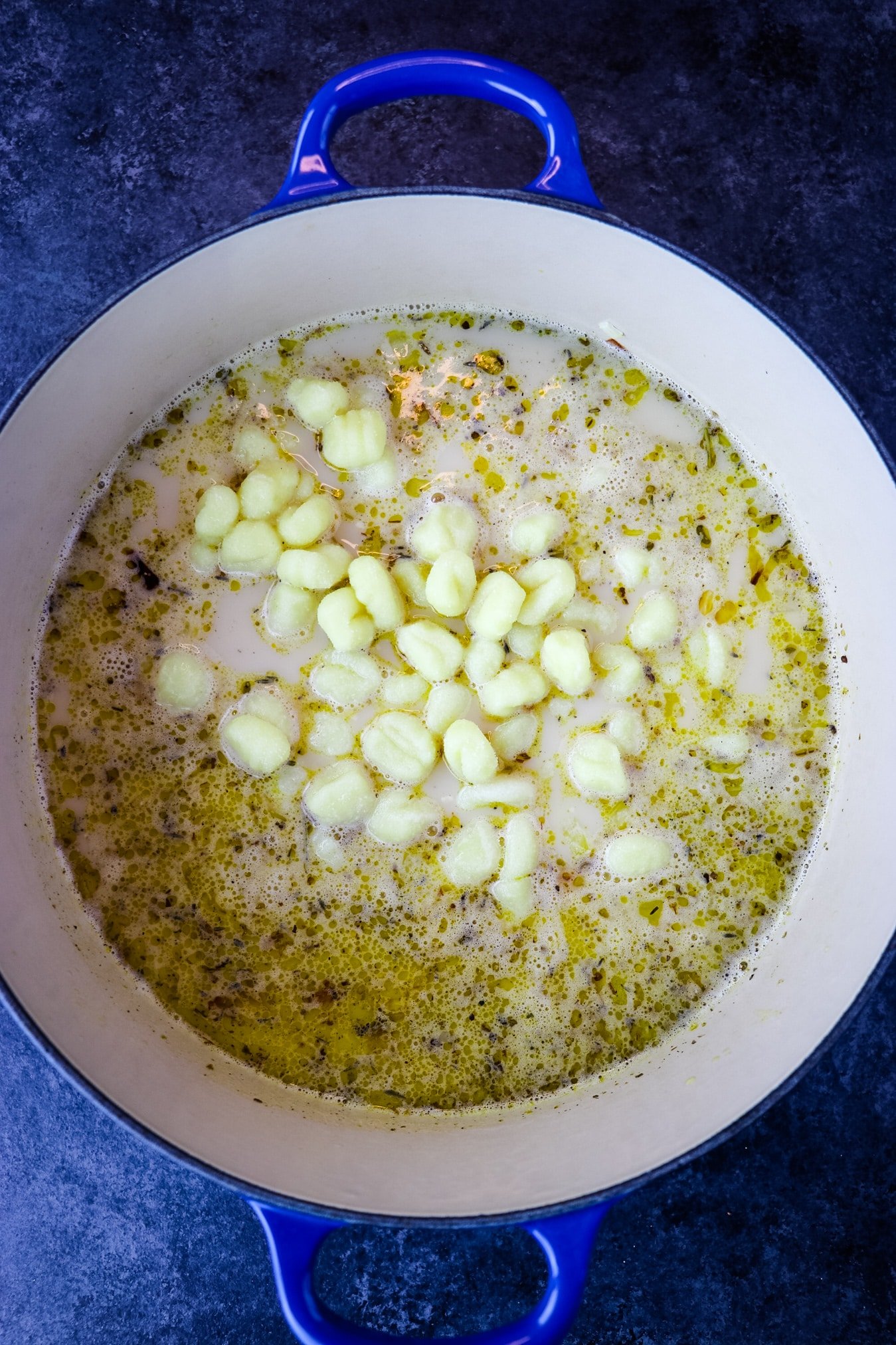 Potato gnocchi added to soup in Dutch oven.