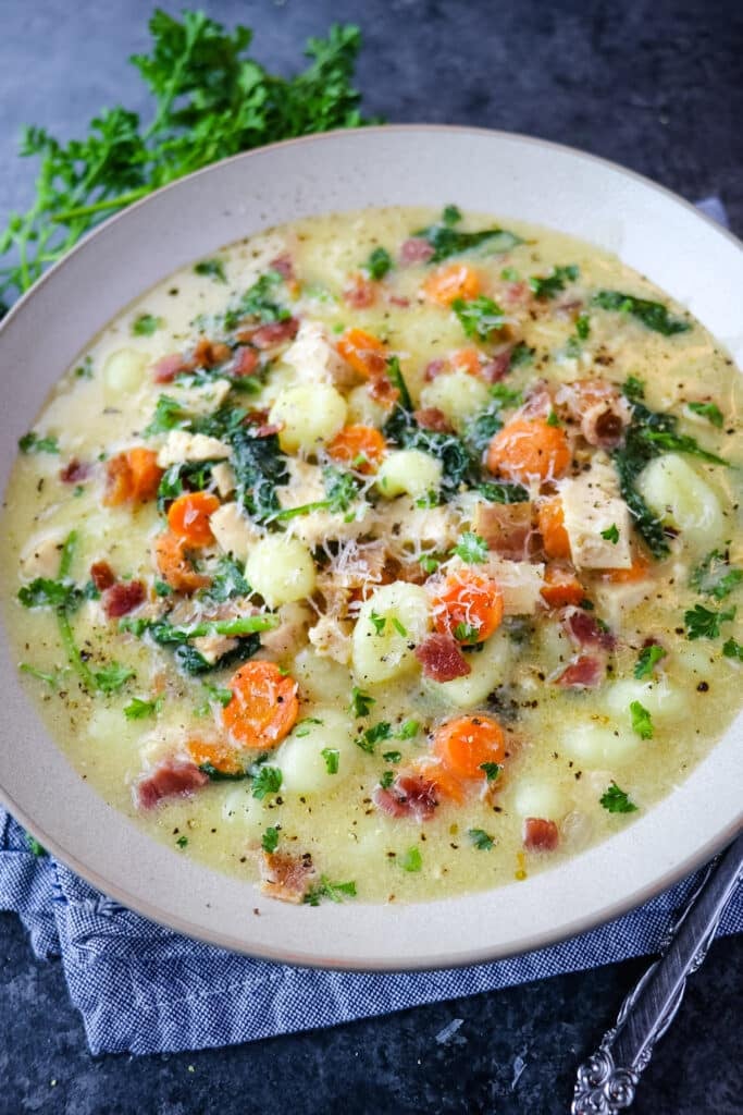 Copycat Olive Garden Chicken gnocchi soup in bowl, topped with grated parmesan cheese.