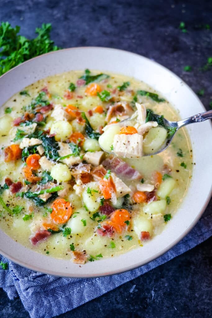 Olive garden chicken gnocchi soup in bowl, with spoon.