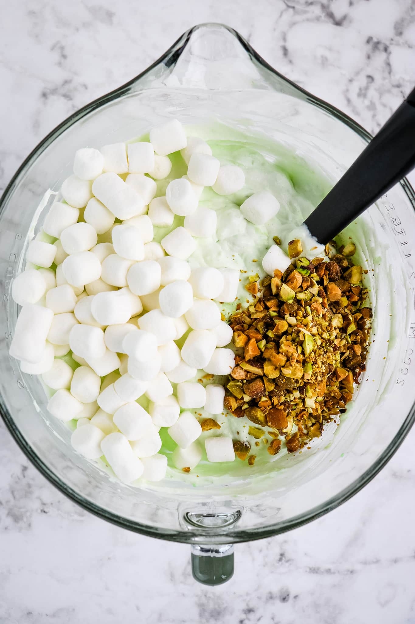 Pistachio fluff with marshmallows and chopped pistachio nuts in a bowl.