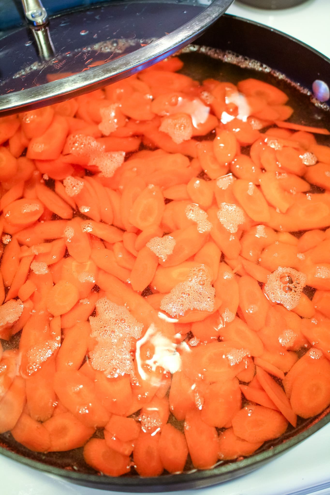 Carrots covered in water in a skillet.