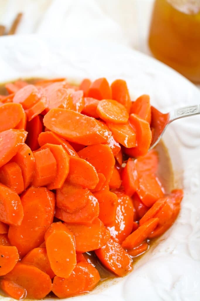 Sauteed carrots recipe in white bowl with serving spoon.