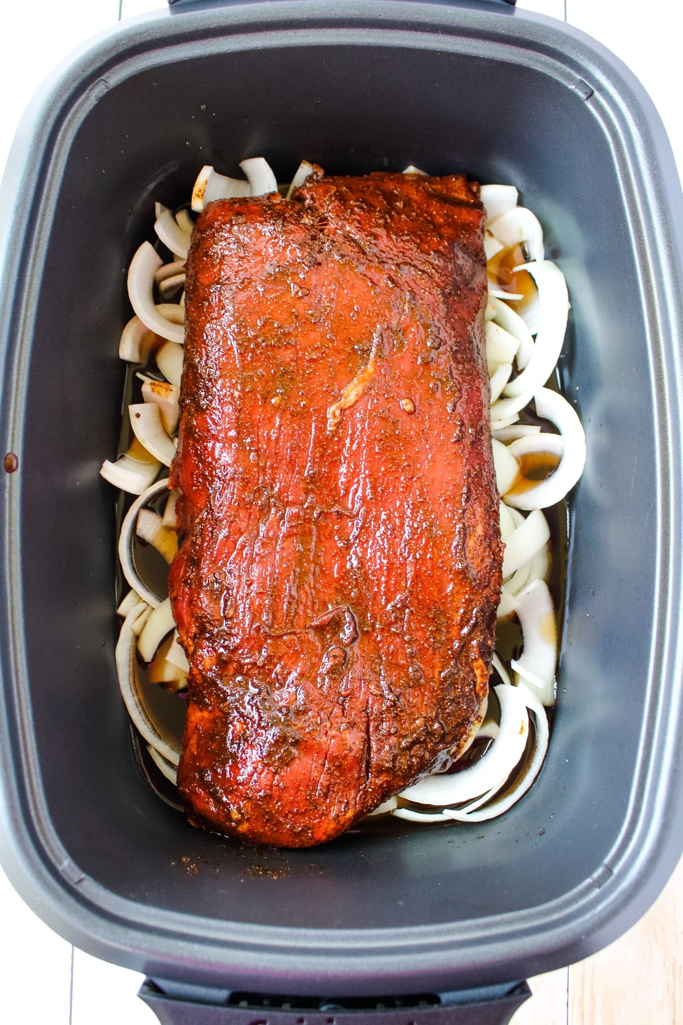 Beef brisked in slow cooker on top of onions and broth.